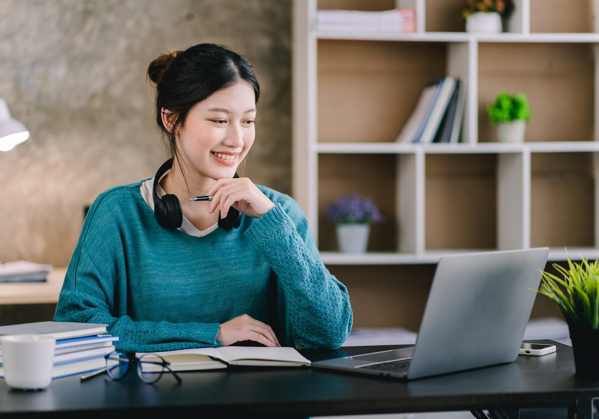 Smart and positive Asian female freelancer or student studying online webinars or courses at home. Video calling and chatting